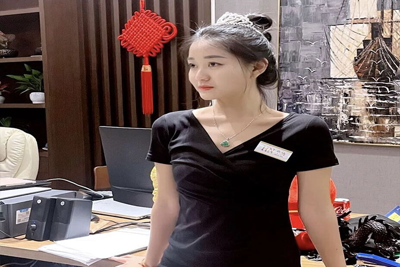 前台客服经理身着黑色制服在大堂服务台值守，佩戴工牌与项链